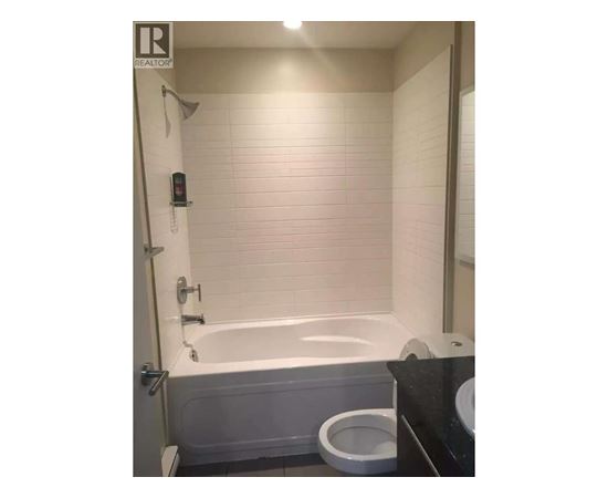A white bathtub is in a bathroom with a toilet and a sink.