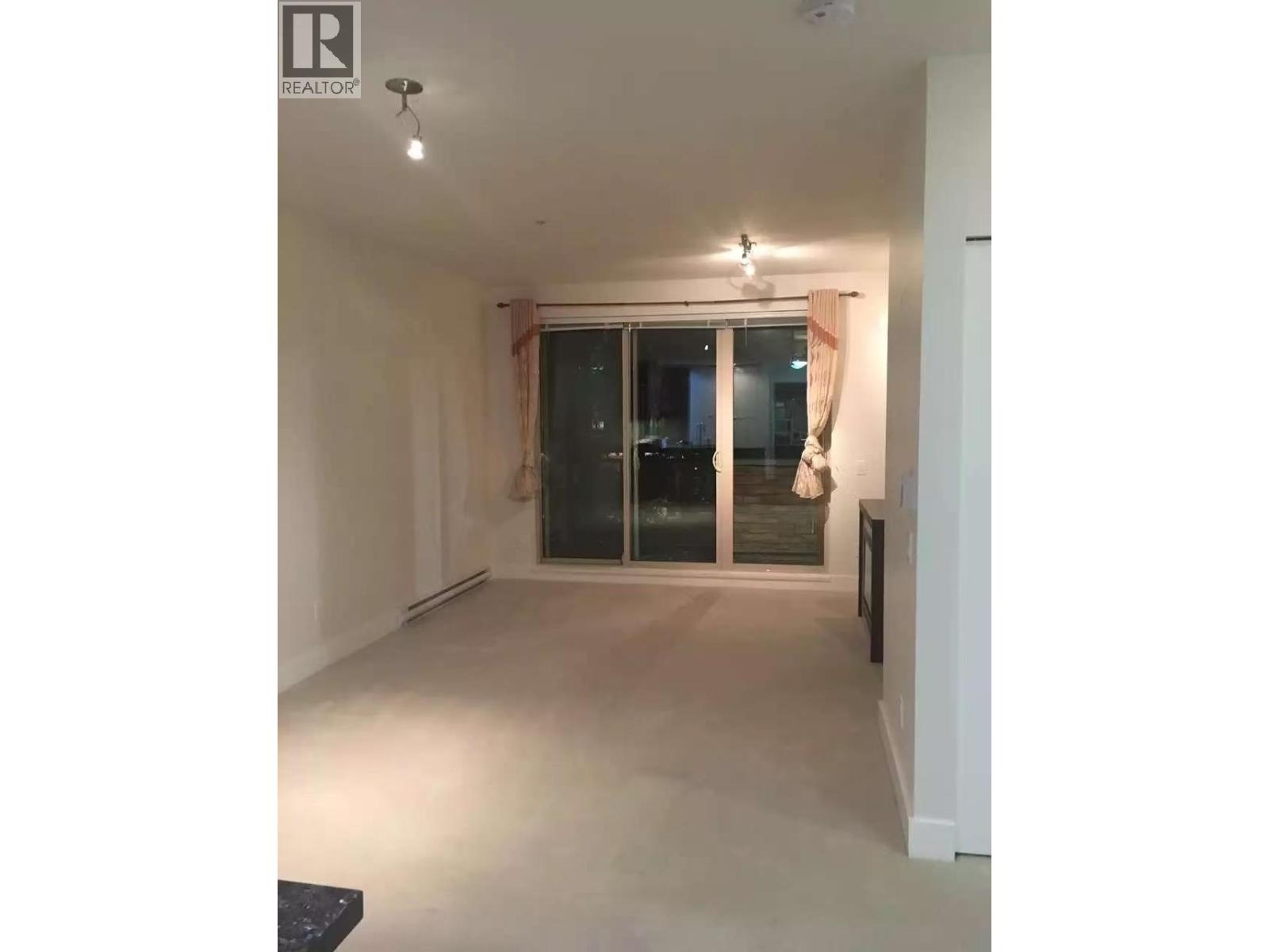 A spacious room with a sliding glass door and a black bench.