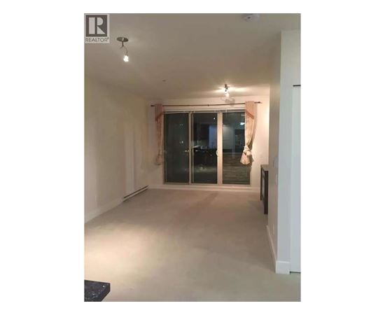 A spacious room with a sliding glass door and a black bench.