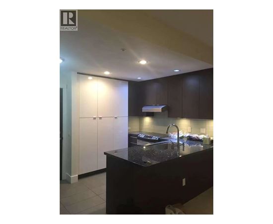 A kitchen with dark brown cabinets and a black countertop.