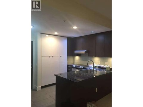 A kitchen with dark brown cabinets and a black countertop.