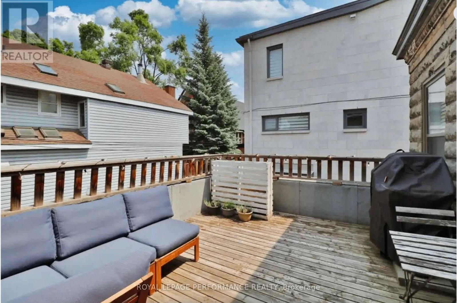 A wooden deck with a blue couch and a grill.