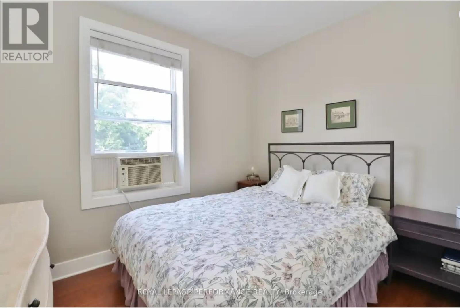 A bedroom with a bed, nightstand, and window.