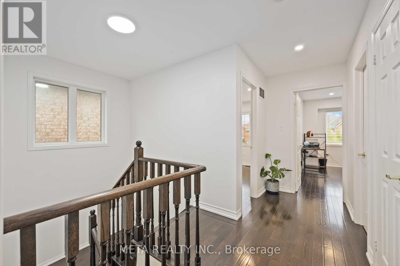 A spacious hallway with a wooden staircase and a potted plant.