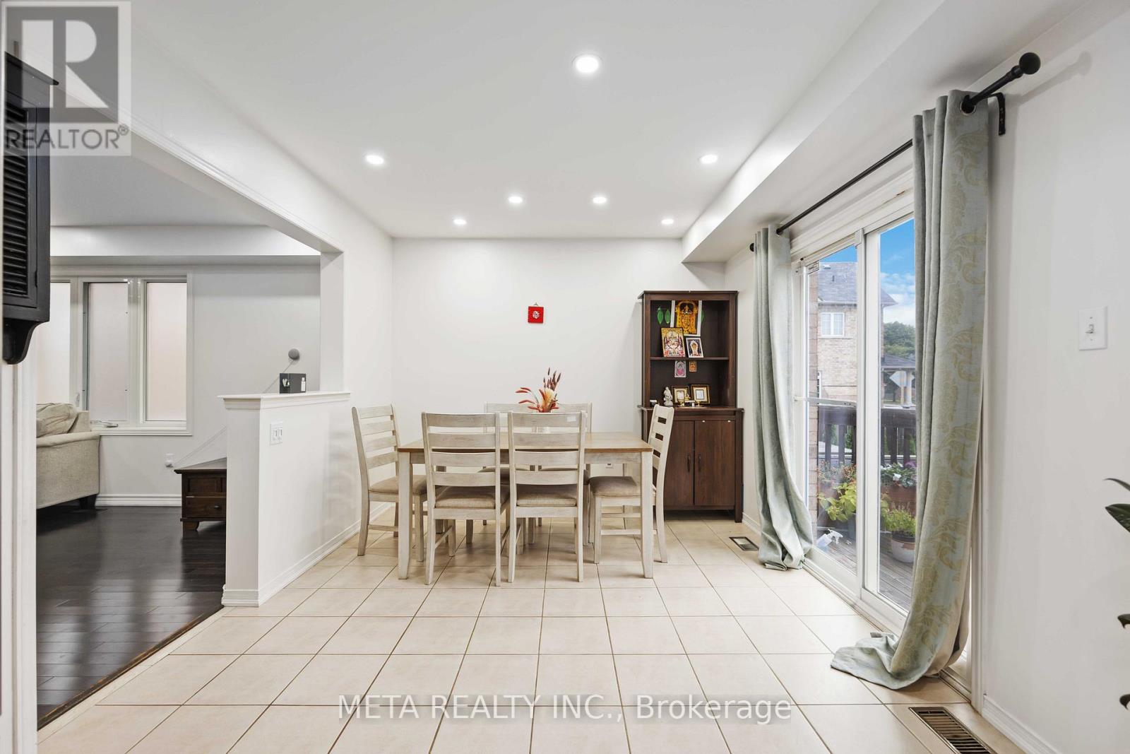 A dining room with a table set for four and a kitchen area in the background.