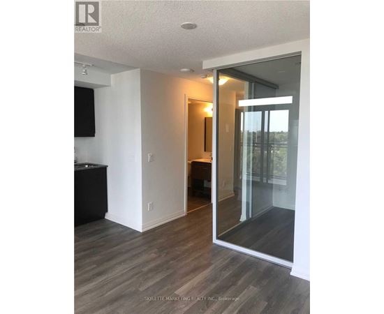 A modern living room with a television and a glass door leading to a balcony.