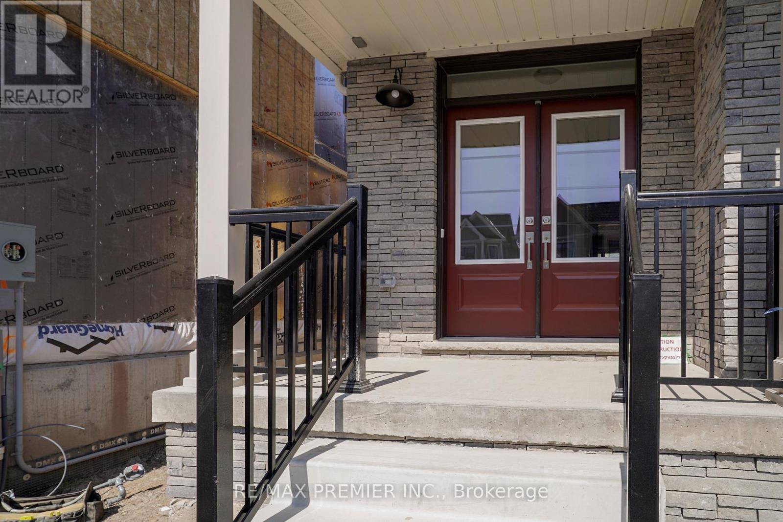 A house entrance with a red door and a black railing.