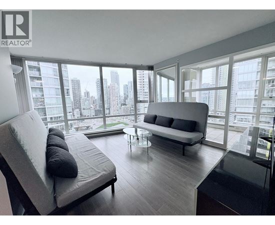 A modern living room with a grey sofa and a glass table.
