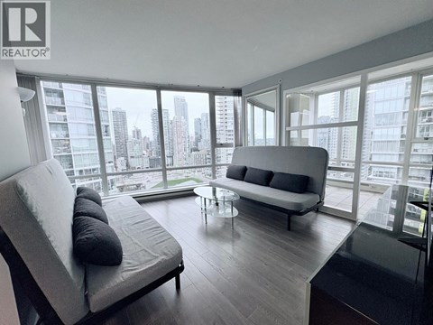 A modern living room with a grey sofa and a glass table.