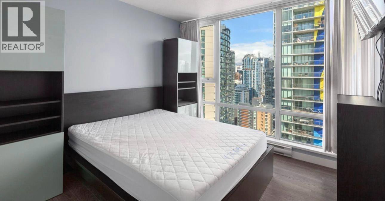 A bedroom with a large bed and a window overlooking a cityscape.