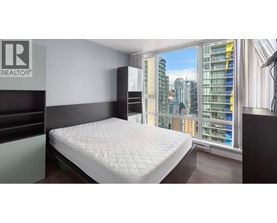 A bedroom with a large bed and a window overlooking a cityscape.