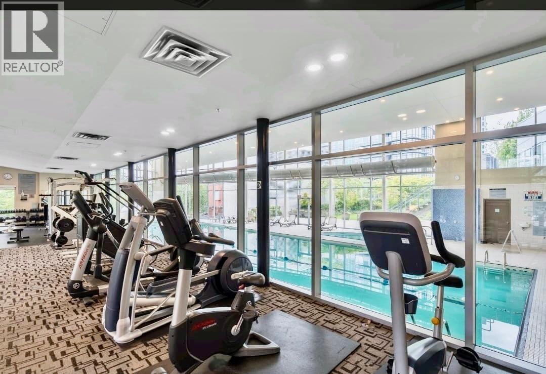 A gym with a row of treadmills and a swimming pool in the background.