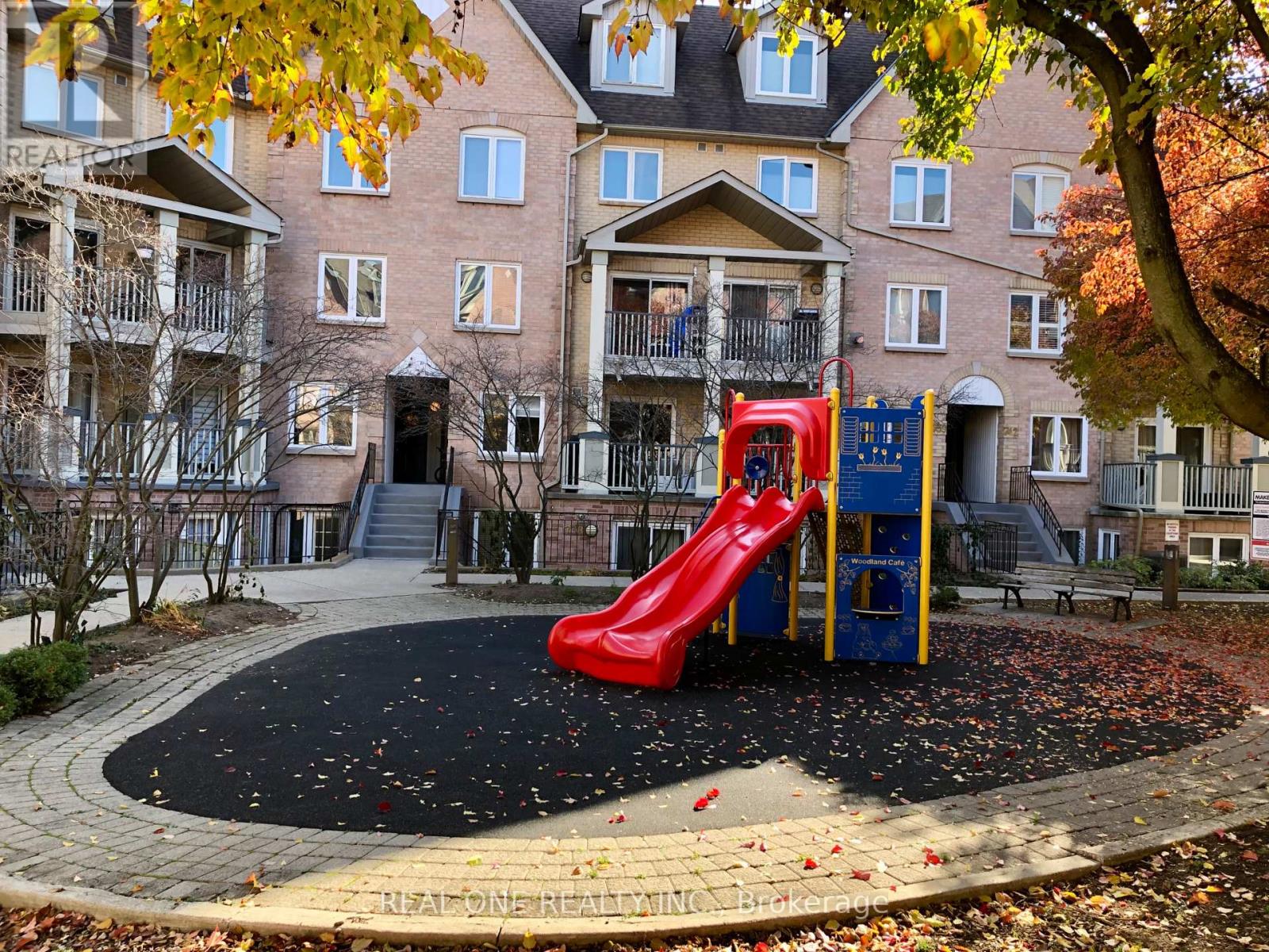 A red slide is in the middle of a blacktop playground.