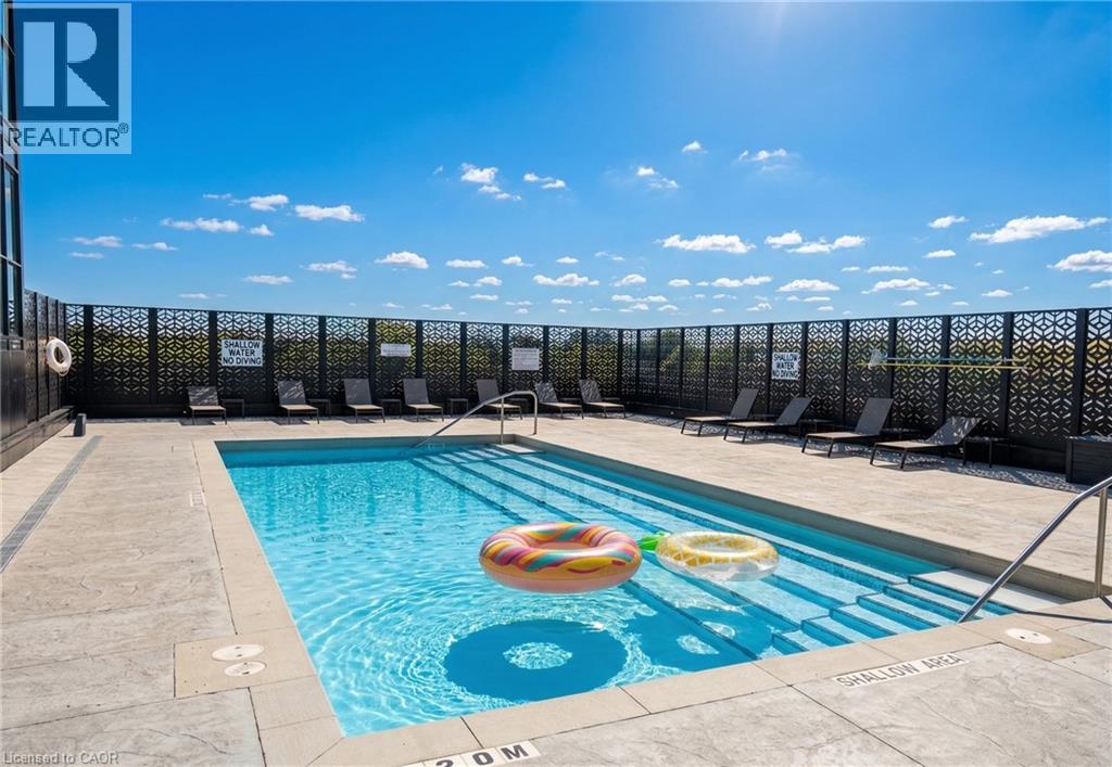 A pool with a blue tiled edge and a black fence in the background.