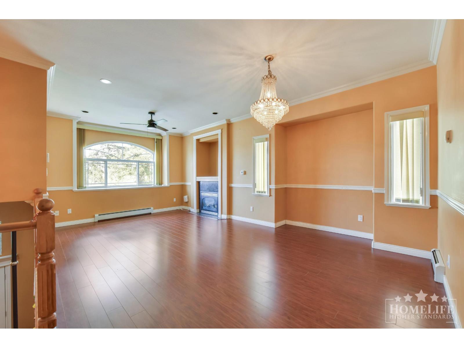 A large empty room with wooden floors and a chandelier.