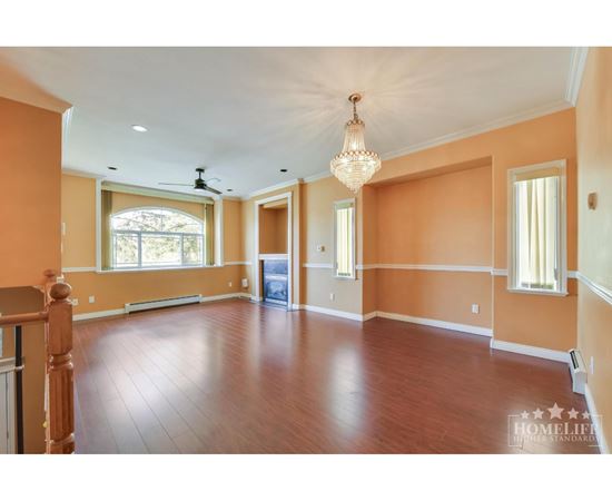 A large empty room with wooden floors and a chandelier.