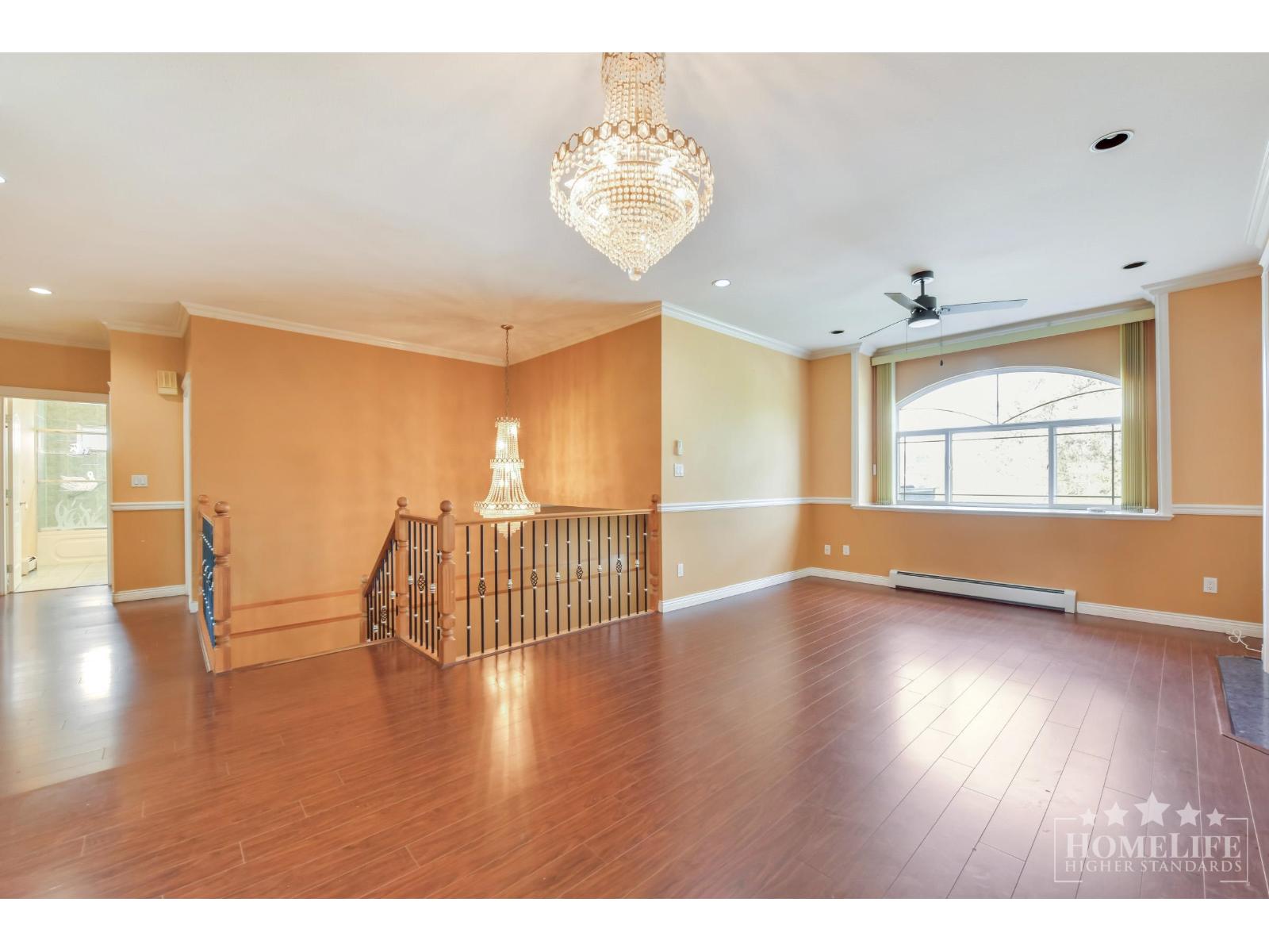 A large empty room with wooden floors and a chandelier.
