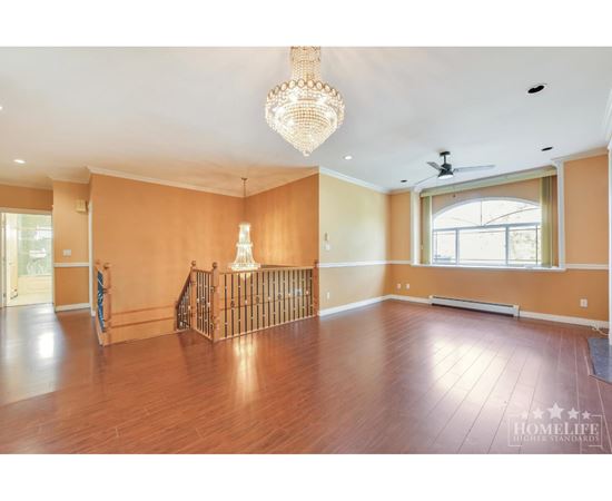 A large empty room with wooden floors and a chandelier.