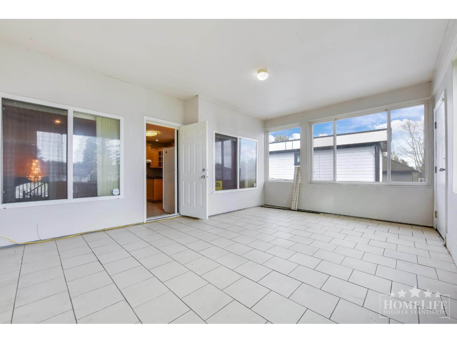 A spacious, empty room with tiled flooring and large windows.