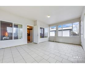 A spacious, empty room with tiled flooring and large windows.