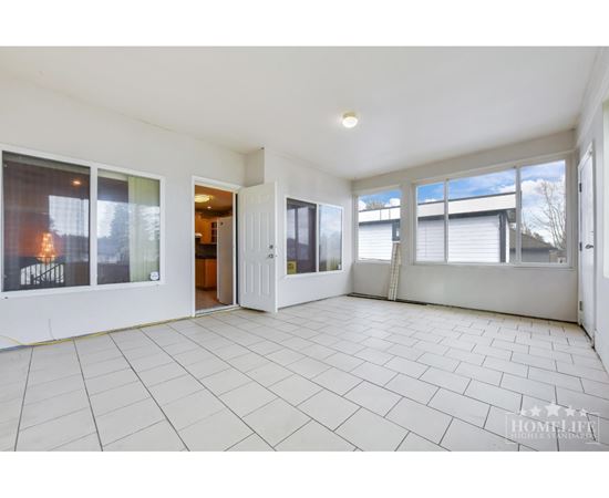 A spacious, empty room with tiled flooring and large windows.