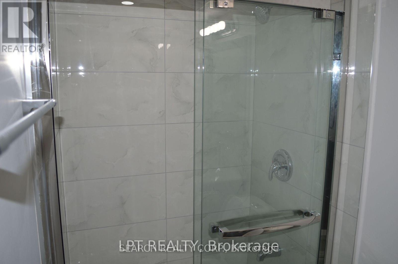 A shower with a glass door and a metal handle.