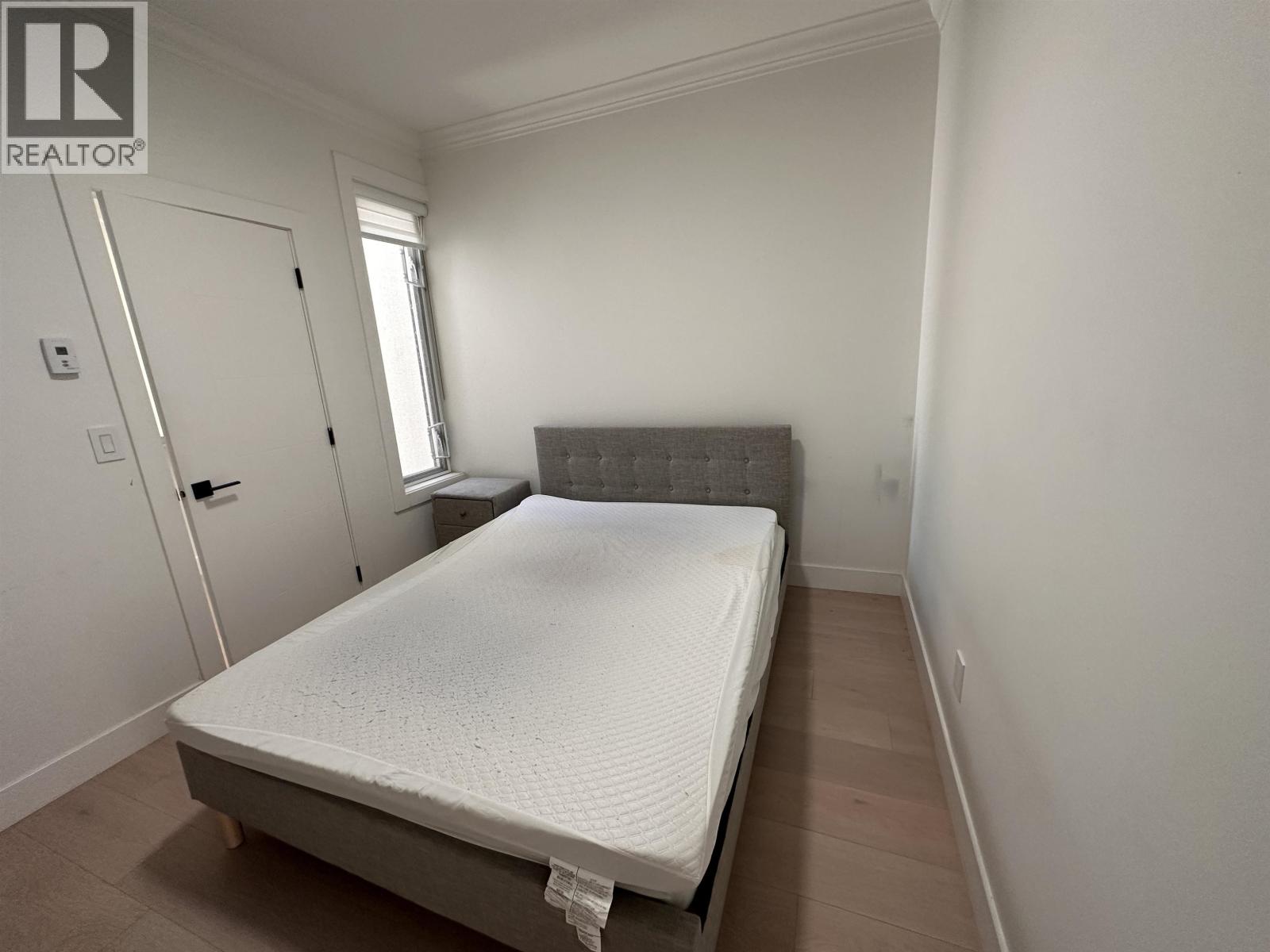 A bedroom with a bed, dresser, and window.