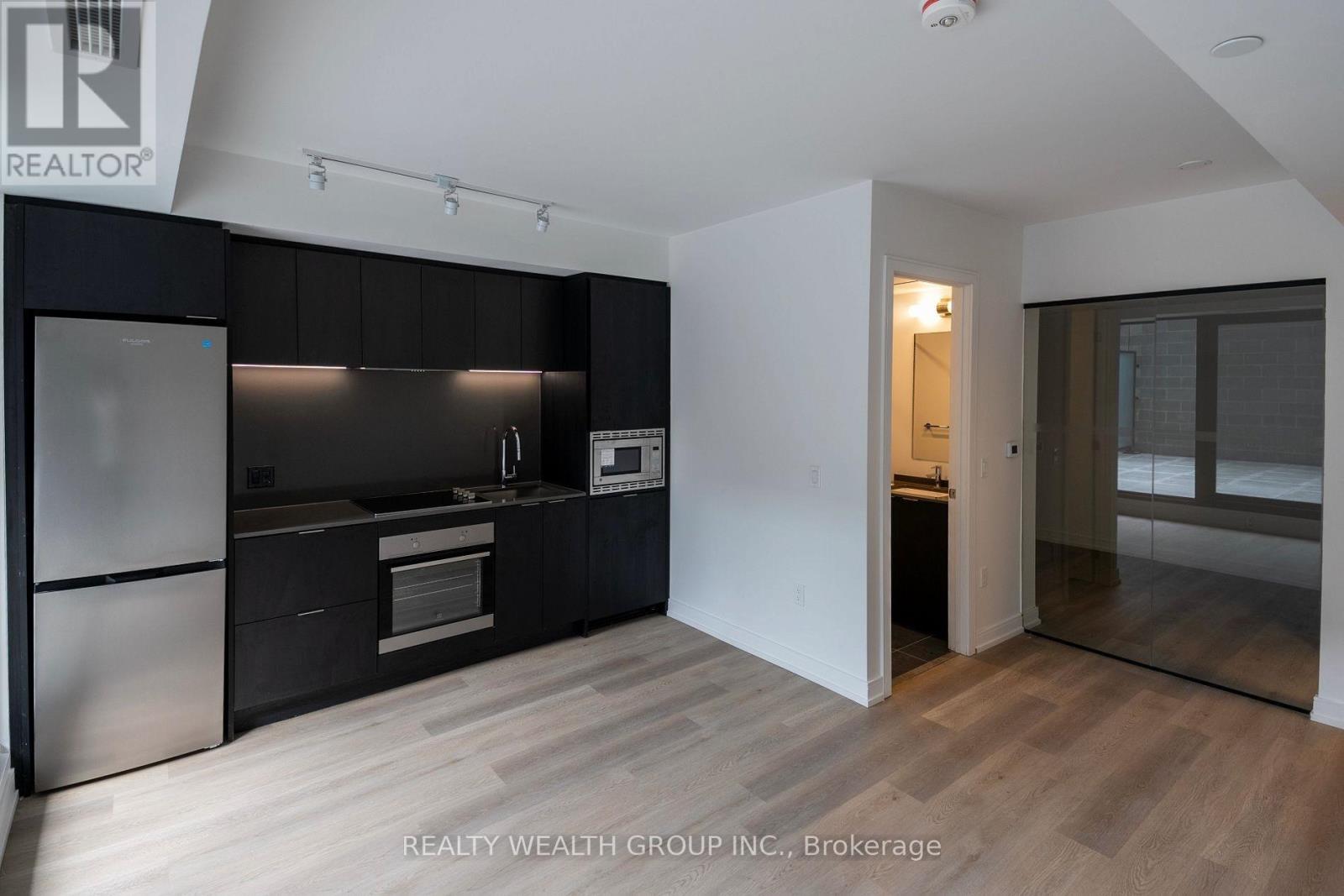 A modern kitchen with a refrigerator, oven, and microwave.
