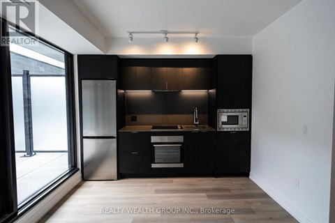 A modern kitchen with black cabinets and stainless steel appliances.
