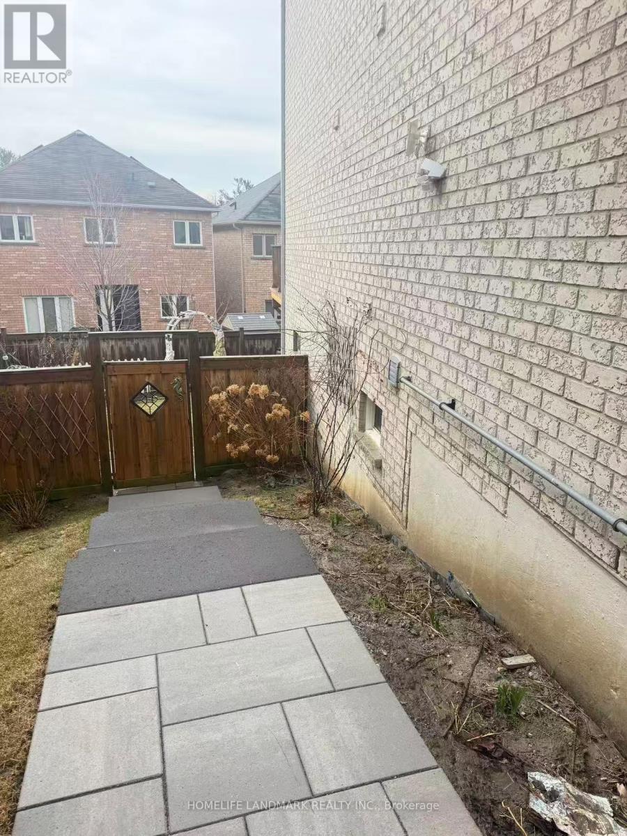 A concrete walkway leads to a wooden gate in a backyard.