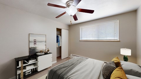 A bedroom with a bed, a ceiling fan, and a painting on the wall.
