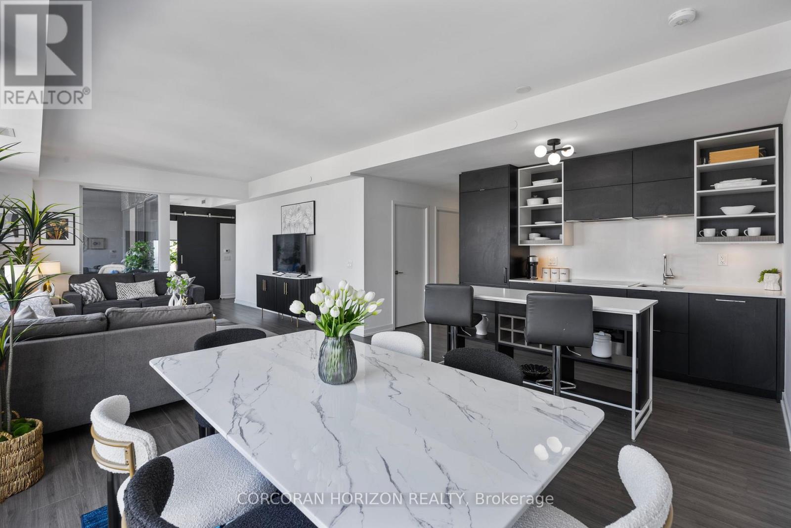 A modern kitchen with a marble table and black chairs.