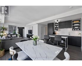 A modern kitchen with a marble table and black chairs.