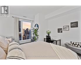 A bedroom with a large bed and a city view through the window.