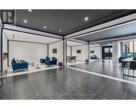 A spacious lobby with blue chairs and a black and white floor.