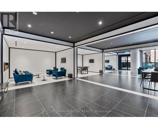 A spacious lobby with blue chairs and a black and white floor.