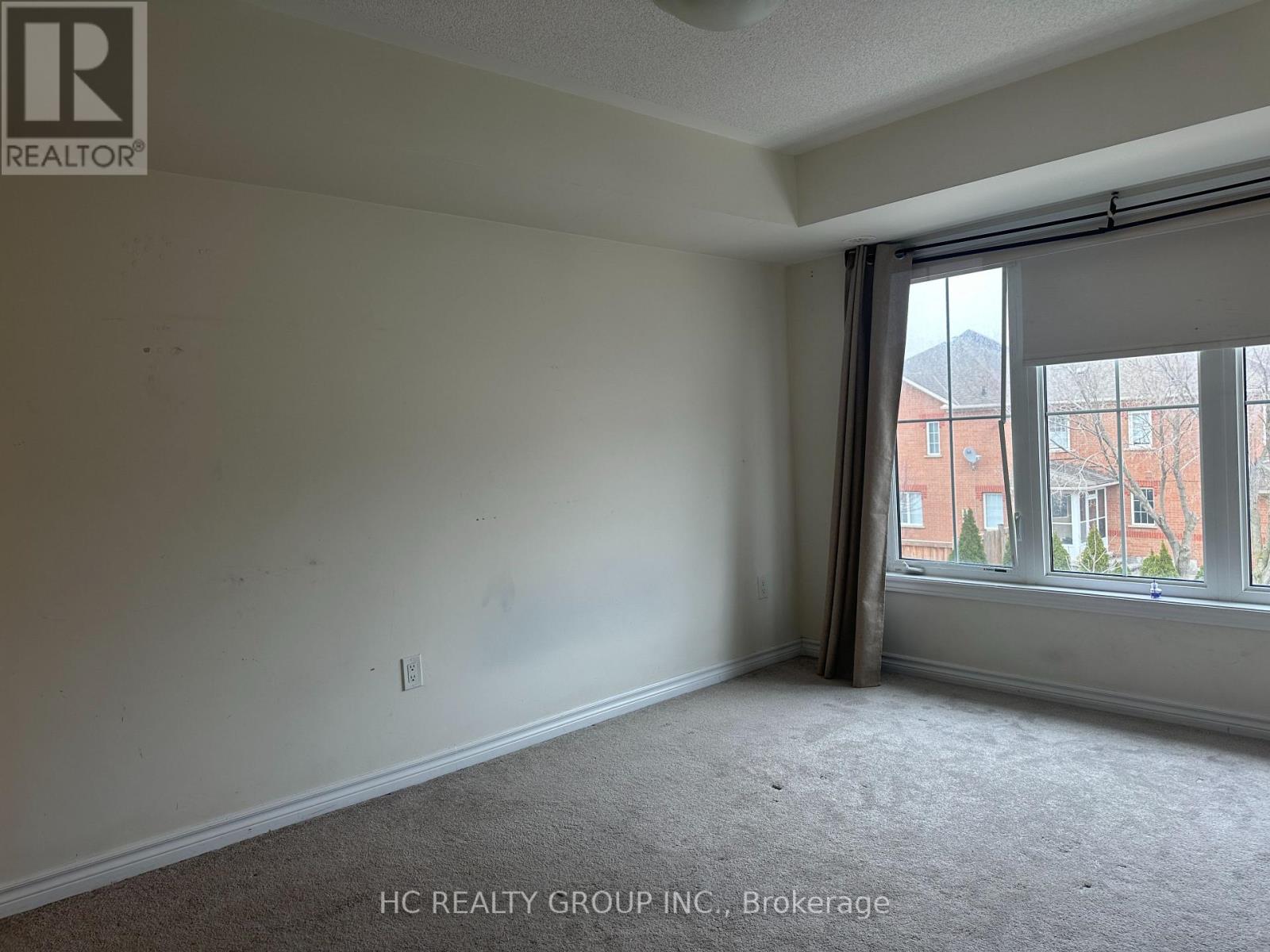 A room with a window showing a view of a red building outside.
