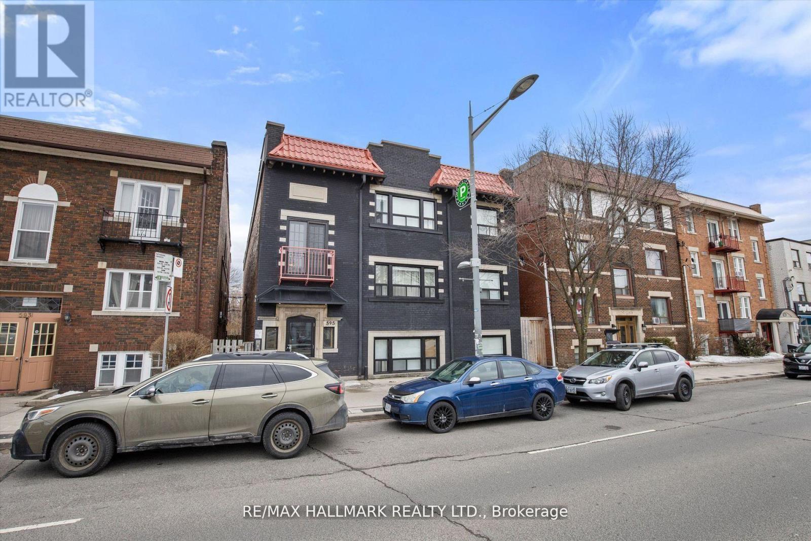 A street view with cars and buildings with the RE/MAX Hallmark Realty logo.