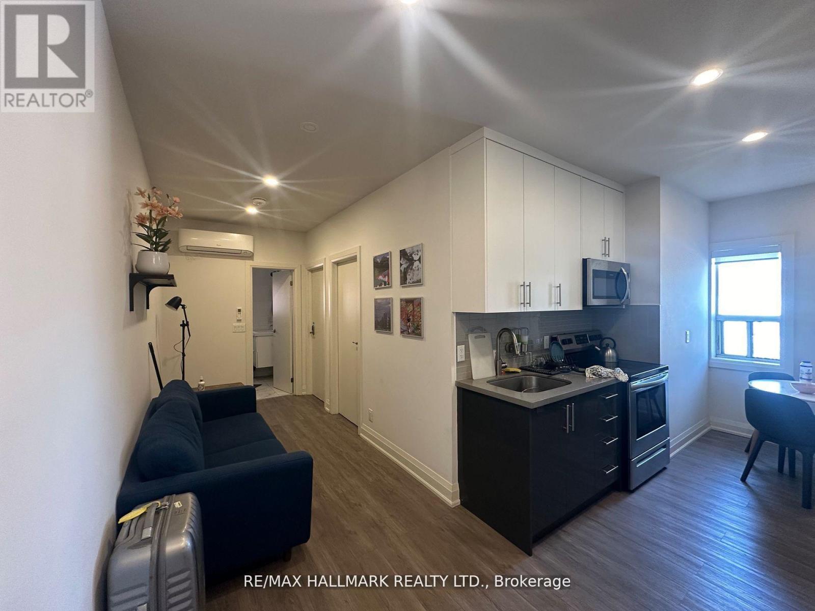 A well-lit kitchen and living room with a couch and a dining table.
