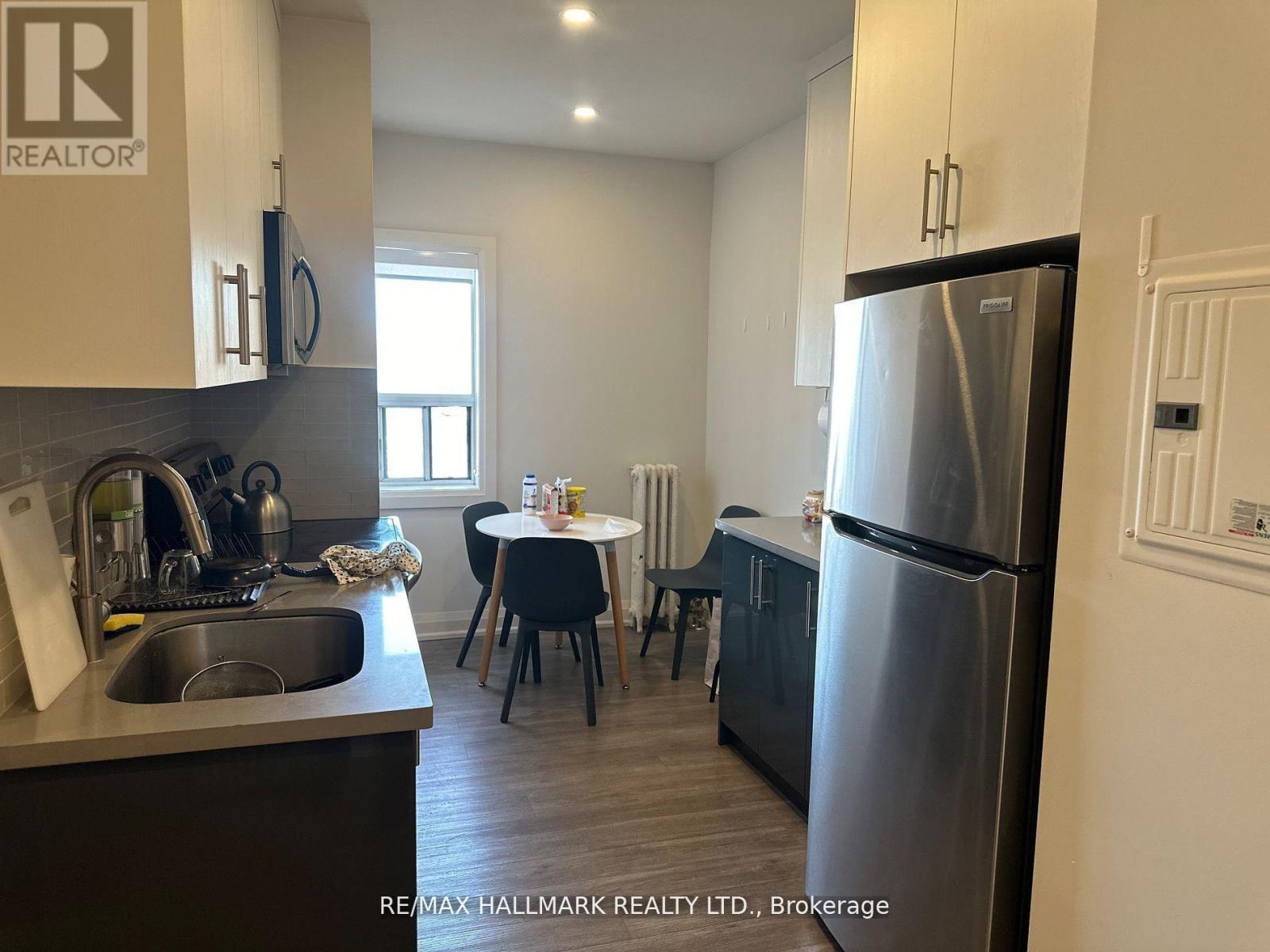 A kitchen with a sink, refrigerator, and a dining table with chairs.