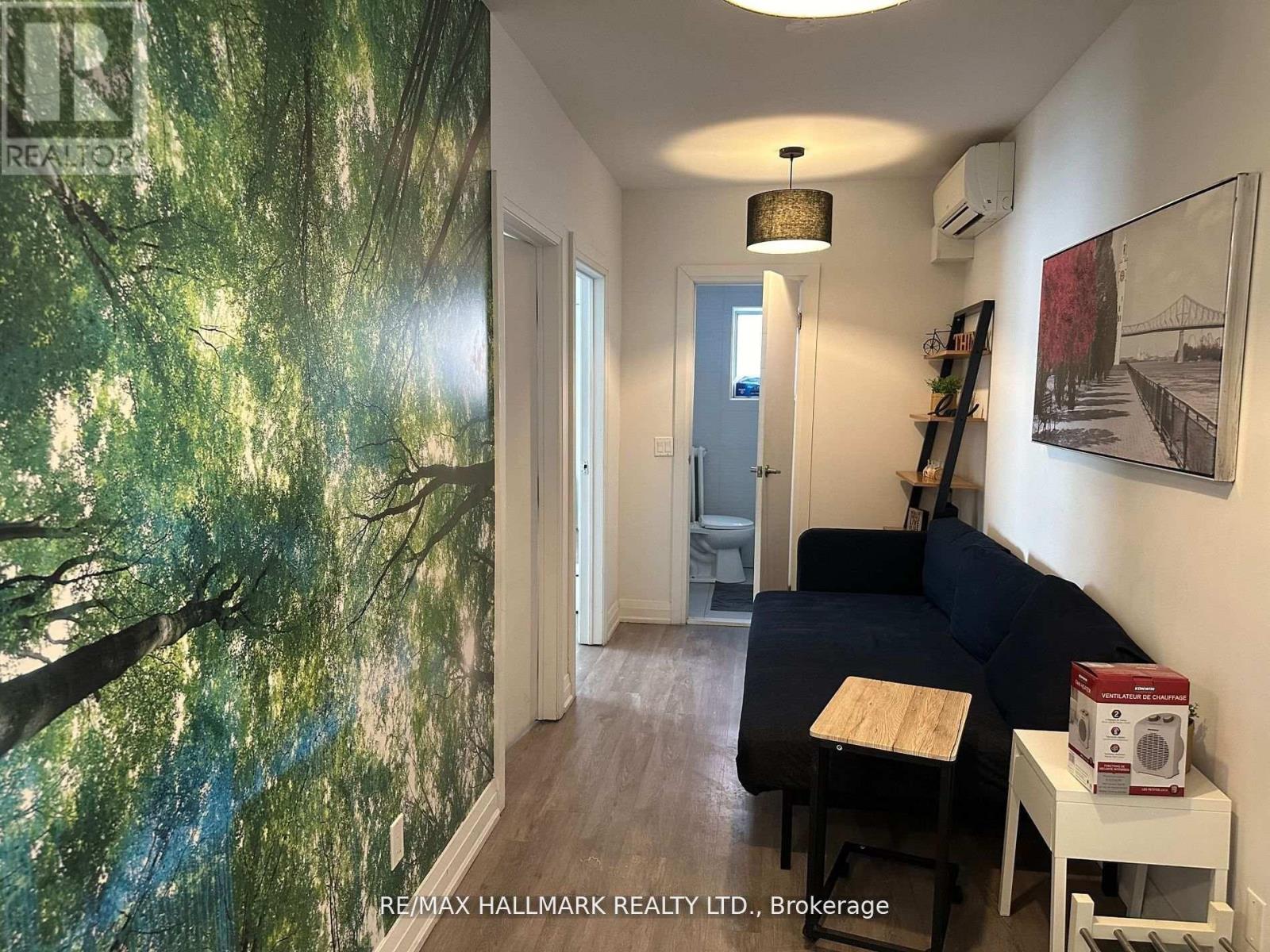 A living room with a couch, a wall mural, and a lamp.