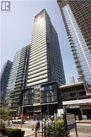 A modern skyscraper with a glass facade stands tall among other buildings.