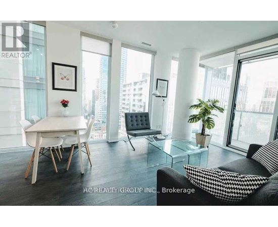A living room with a couch, a dining table and a plant.