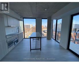 A modern kitchen with a table and chairs in the foreground and a view of the city through the windows.