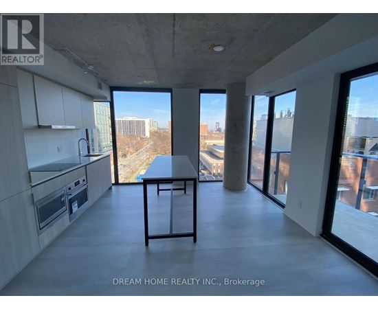 A modern kitchen with a table and chairs in the foreground and a view of the city through the windows.