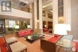 A living room with a couch, chair, and a table with a lamp on it.
