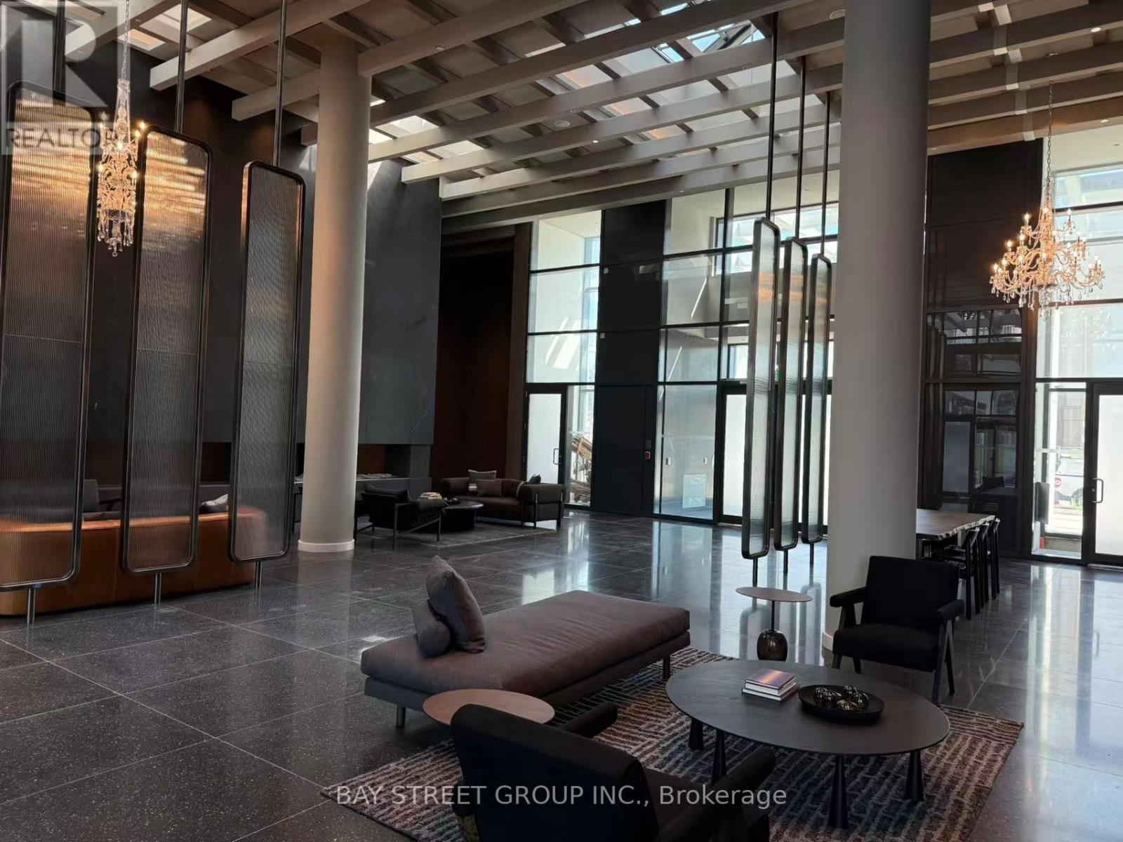 A spacious lobby with a chandelier, sofas, and a coffee table.