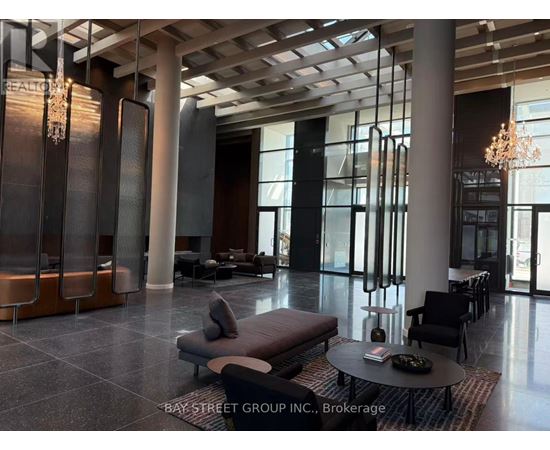 A spacious lobby with a chandelier, sofas, and a coffee table.