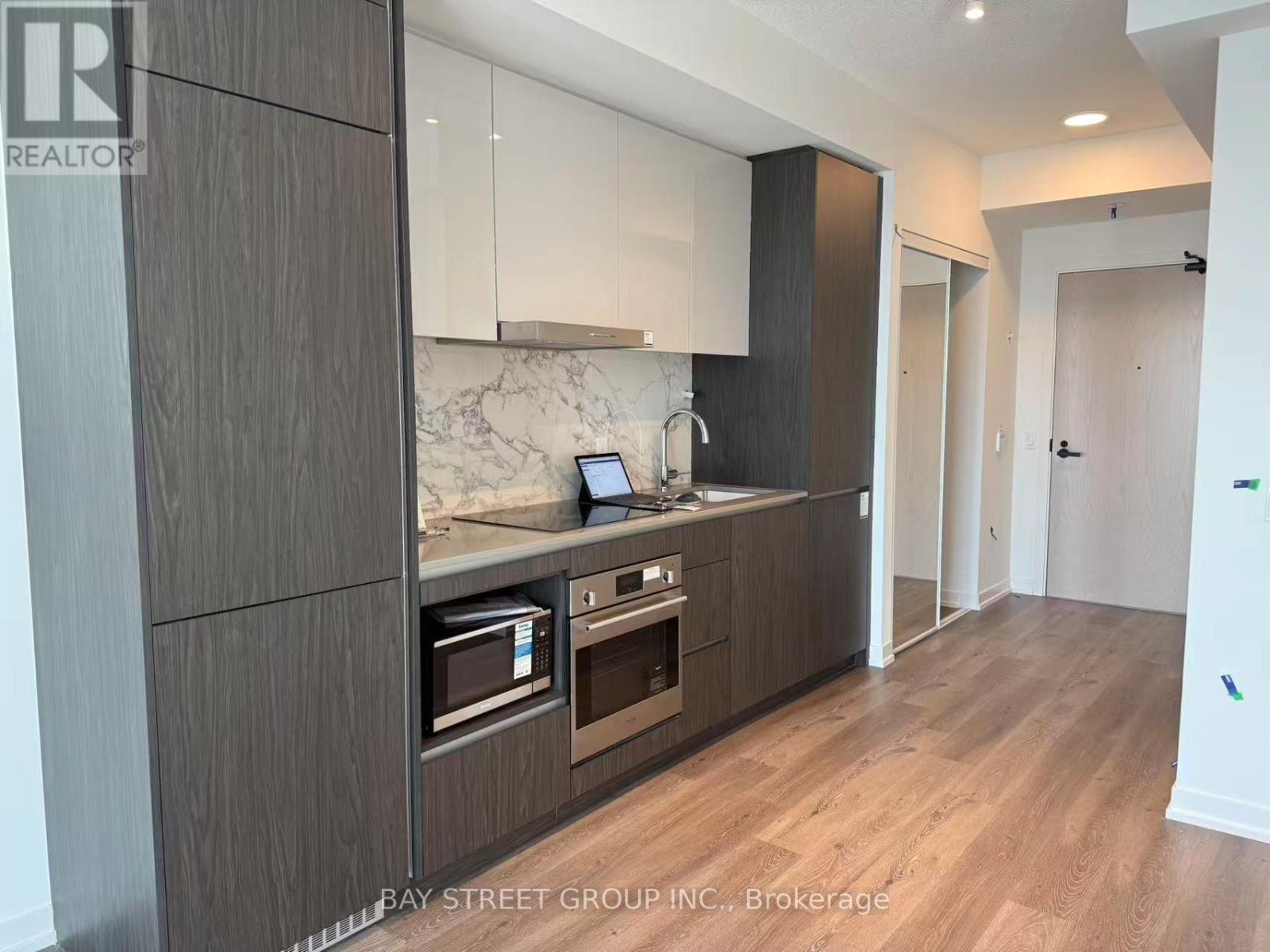 A modern kitchen with dark wood cabinets and a marble countertop.