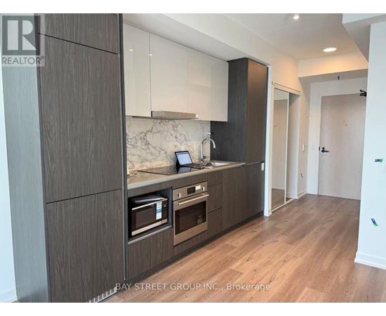 A modern kitchen with dark wood cabinets and a marble countertop.